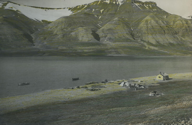 Bildet viser en gruveleir ved siden av en fjord, med spredt bebyggelse.