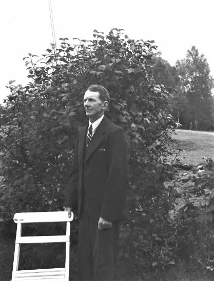 Bygdefotografen Hugo Bengtsson fotograferad på 50- årsdagen vid en trädgårdsstol i sin trädgård i Dämhult. Se även HB275.