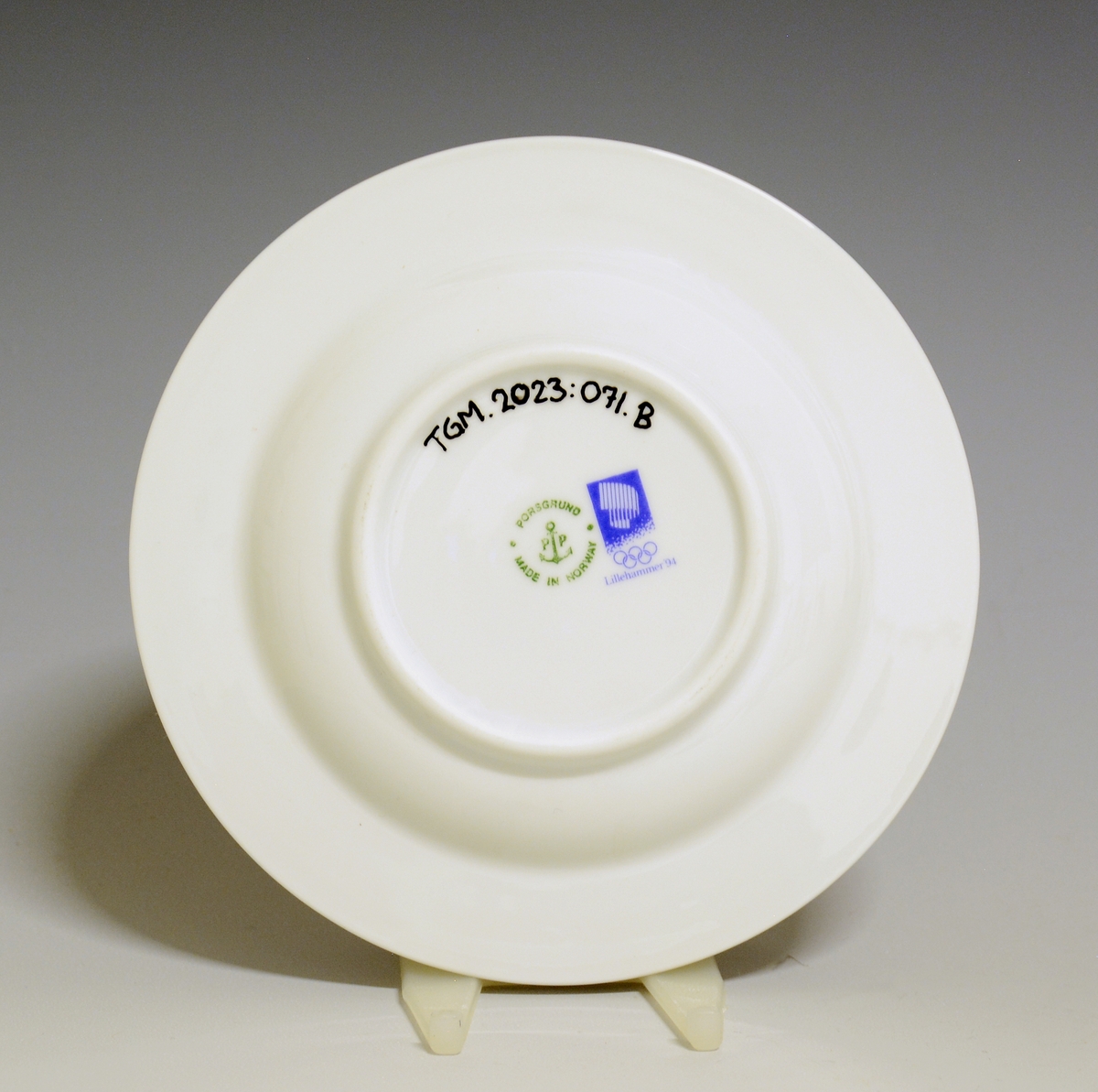 Kaffeskål av porselen med hvit glasur. Dekorert med den offisielle dekoren til Lillehammer OL 1994, rand i blått, grønt og rosa.
Modell: Saturn av Grete Rønning.
