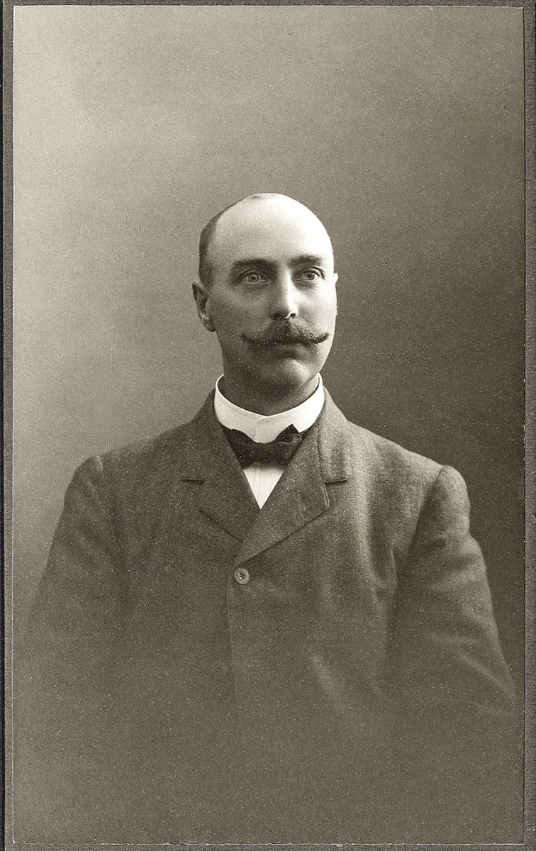 En man i kostym med stärkkrage och fluga. 
Midjebild, halvprofil. Ateljéfoto.
Handlande Carl Ljunggren (1873-1956), Strömsnäsbruk.