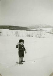 En liten gutt på ski. Han har på seg strikkejakke. Tekst i a