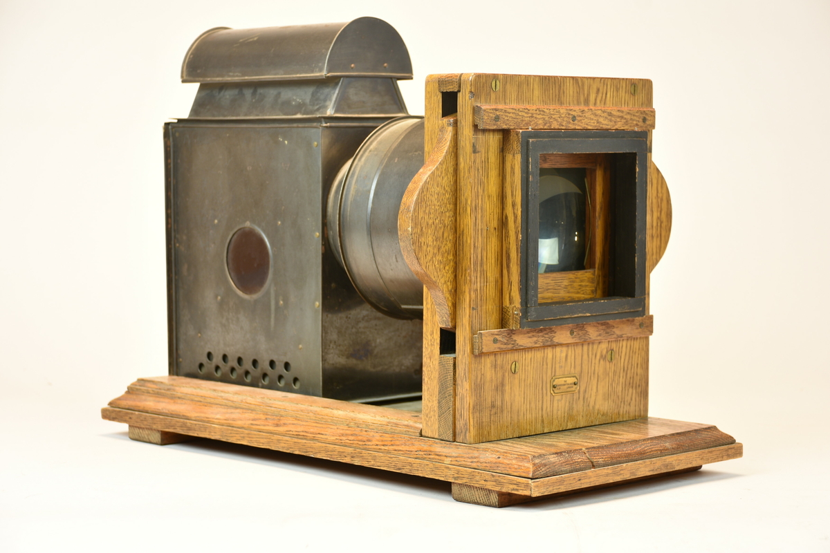 Förstoringsapparat med stativ av trä och lamphus med lock respektive objektiv av plåt. Elektrisk belysning. Avmaskningsram märkt "9x12" samt yttre träram. 
Märkt Henry B. Goodwin på flera delar.