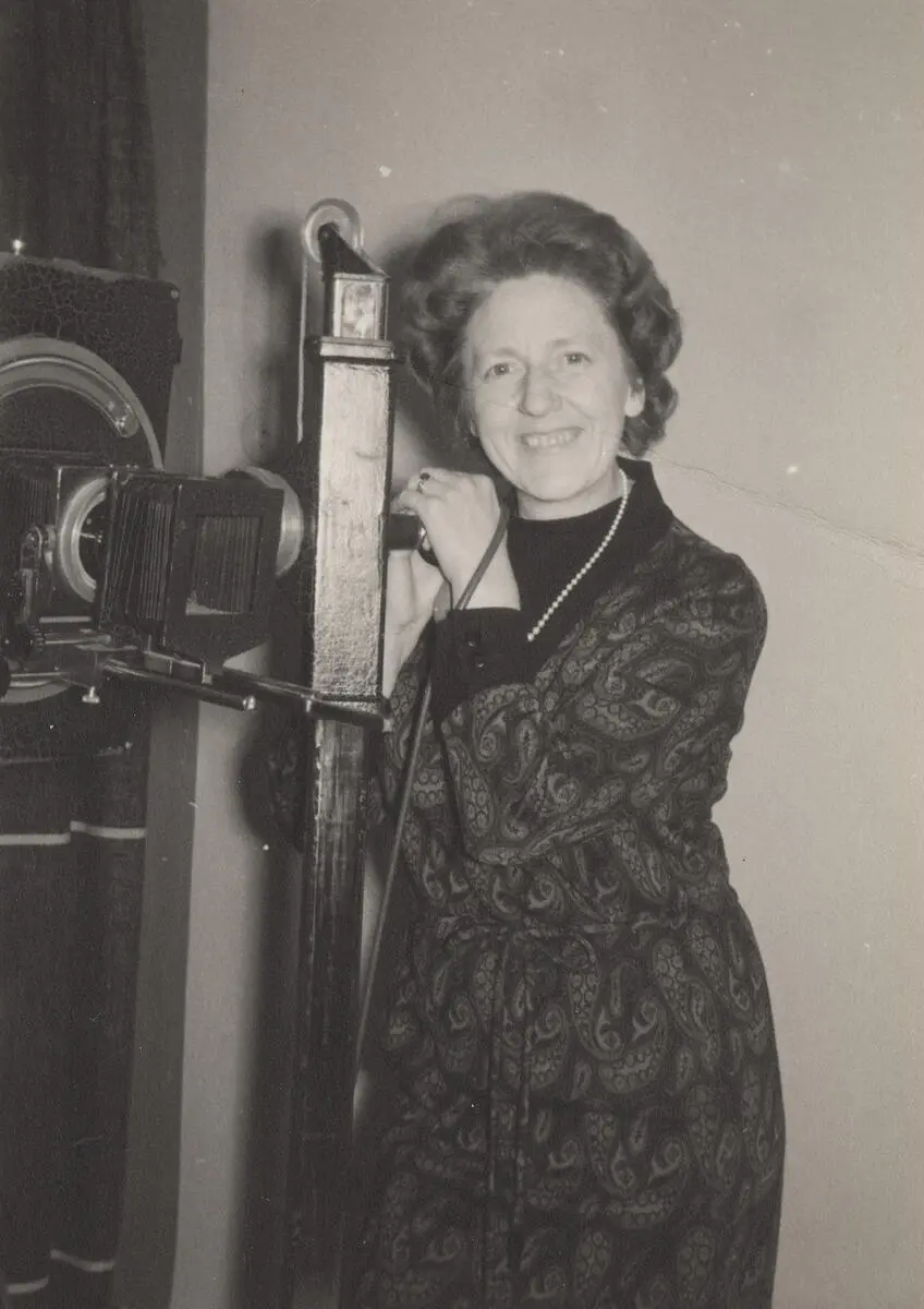 Kvinnelig fotograf poserer med eldre storformat platekamera