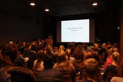 Publikum i auditoriet i Wergelands Hus ser på en presentasjon på lerret