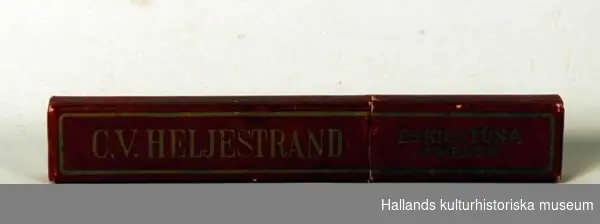 Rakkniv av stål. I röd ask (b), med firmatexten: "C.V. Heljestrand, Eskilstuna, Sweden". b) En röd ask.