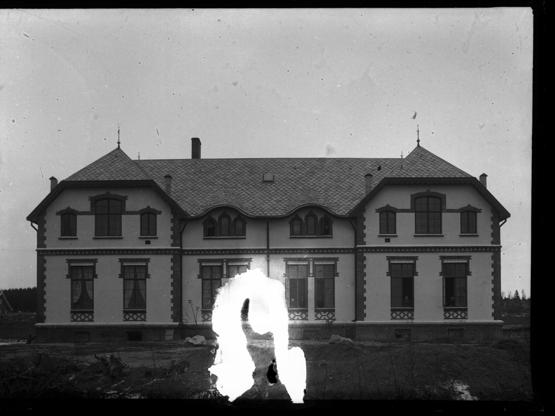 Murbygning på Bastøy. Bastøy skolehjem var i drift fra 1900 til 1970 på øya Bastøy i Oslofjorden. Personer ser ut av vinduene.
