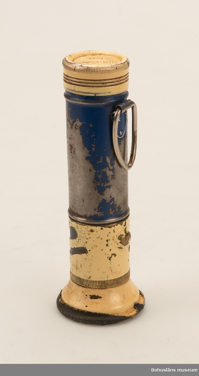 Cylinderformad ficklampa av blå och gulmålad plast. Av märke "Pertrix".
