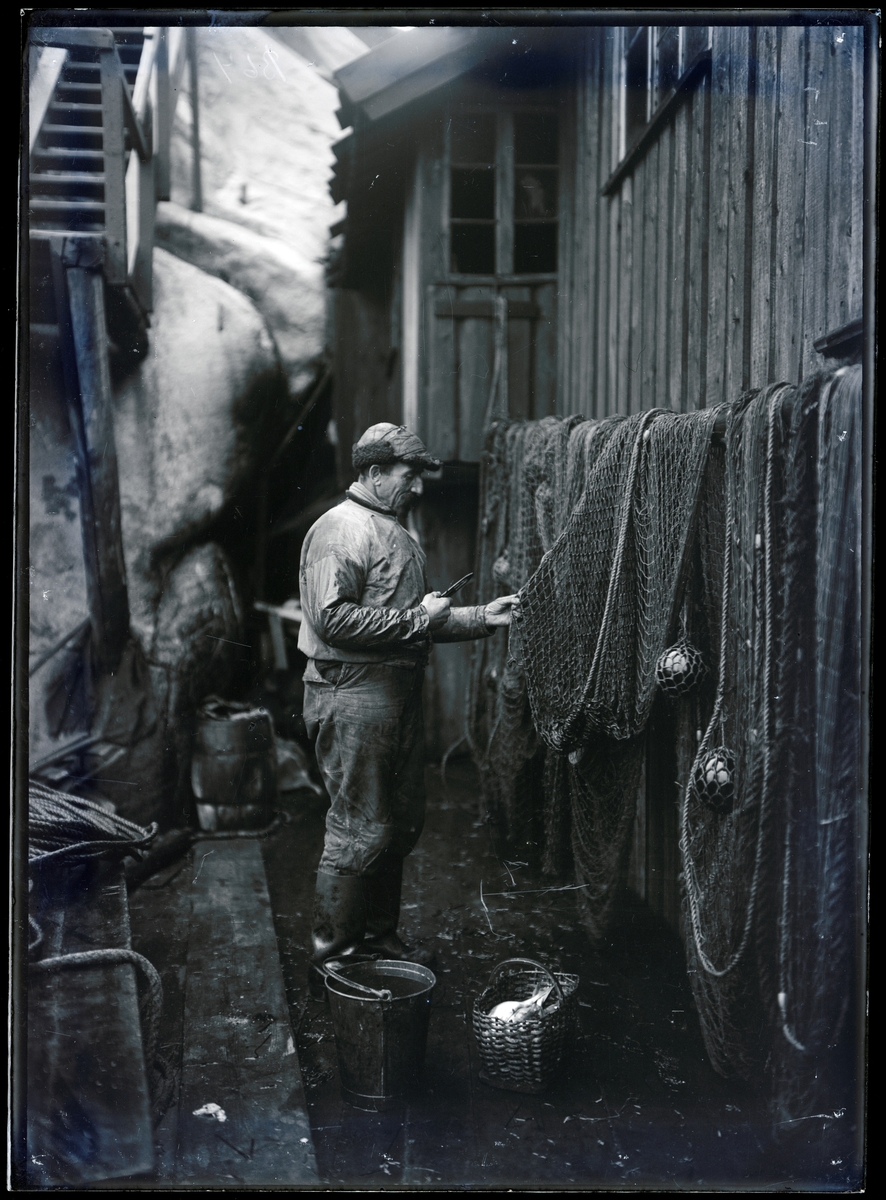 1924 (Ca). Fiskare lagar "snurrevad", vid sjöbodsvägg.