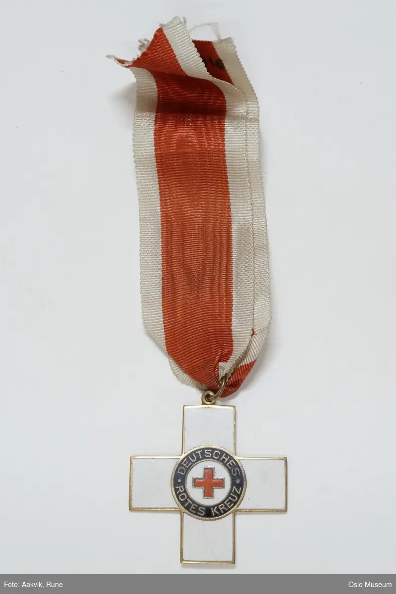 Et kors i hvit emalje, med et rød kors i midten.