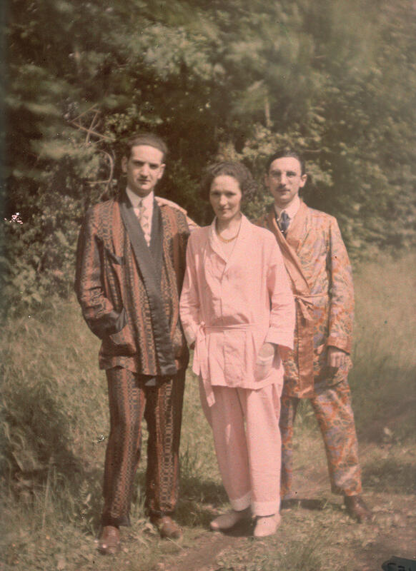 Tre mennesker, en kvinne med en mann på hver side, i silkekimonoer ser mot fotografen. Fargene i fotografiet er duse, og fotografiet er kornete og litt uskarpt.