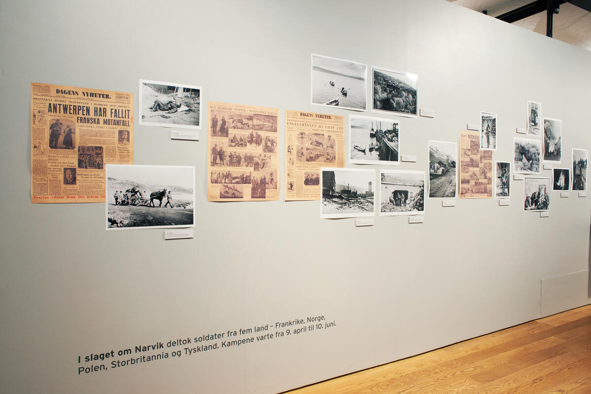 Utstillingsvegg med avisklipp og fotografier montert tett sammen.