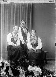 Tre kvinner sittende i studio. Alle kledd i bunad med vippe 