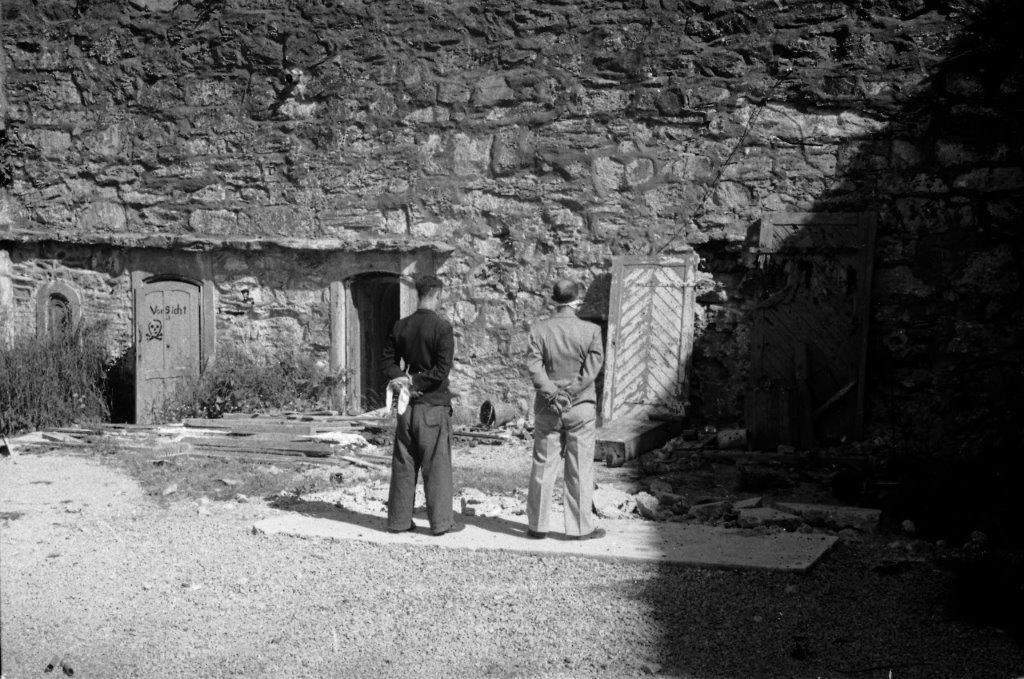 To mannlige figuranter står på stedet ved festningsmuren, der motstandsfolk ble henrettet under 2. verdenskrig.