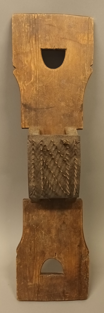 Linhekle laga av ei treplate med handtak i eine enden. På treplata er det sett på ein kloss med mange spisse jernpiggar.
Bak på linhekla er det skore inn bokstavane TOD og KJ og årstalet 1797.