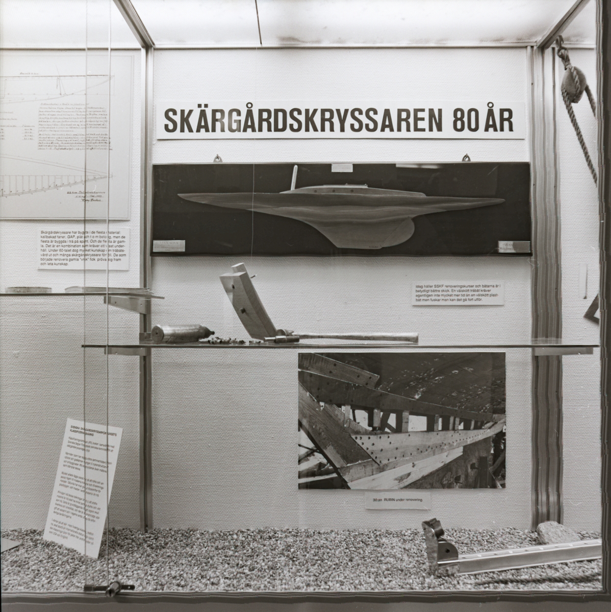 Utställningen "Skärgårdskryssaren 80 år" i trappmonter. Detaljbild av montern med halvmodell i fokus.