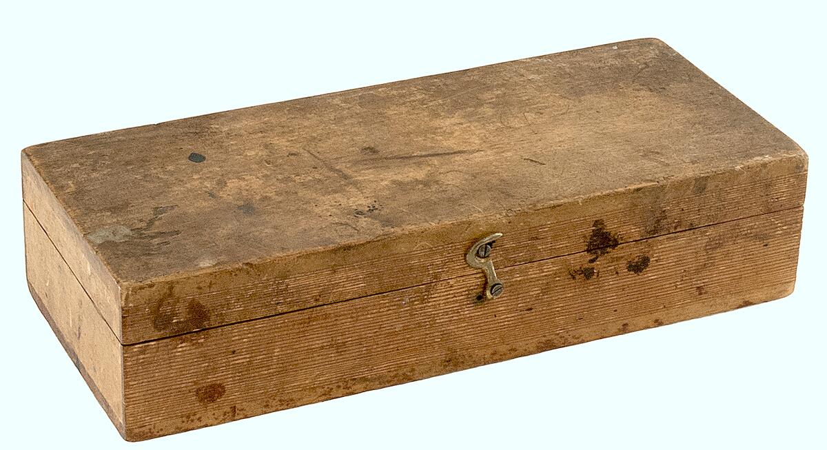 Låda av trä med planimeter ?, lådan är nött och har fläckar, locket stängs med en hake, planimetern är av brunt trä och metall och försedd med en graderad åttkantig mätskiva.
lantmäteri-instrument I trälåda, längd 260, br. 115 mm.