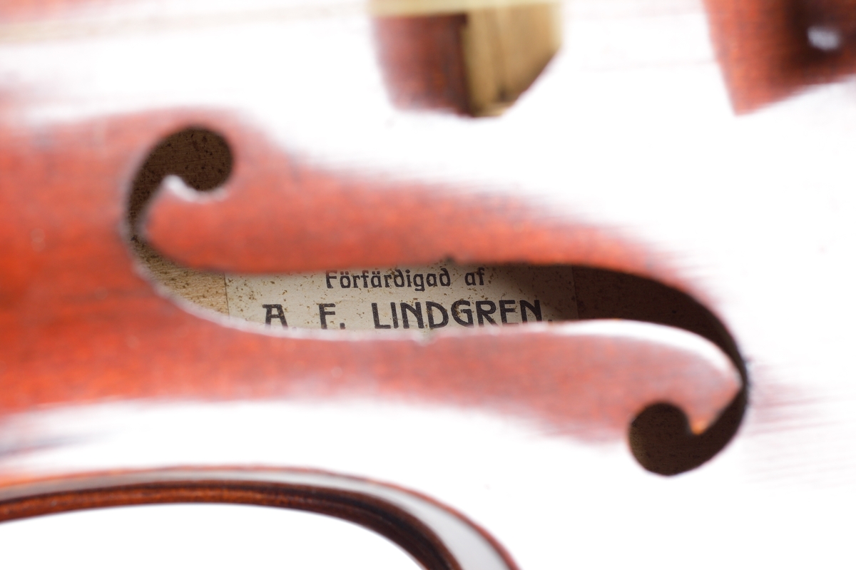 En st. fiol av rött polerat trä. tre strängar. Å baksidan två glödritade stjärnor. Inuti finns etikett: "Förfärdigad av A.F. Lindgren, Instrumentmakare, Västervik 1916". 

Inskrivet i huvudkatalog 1931.