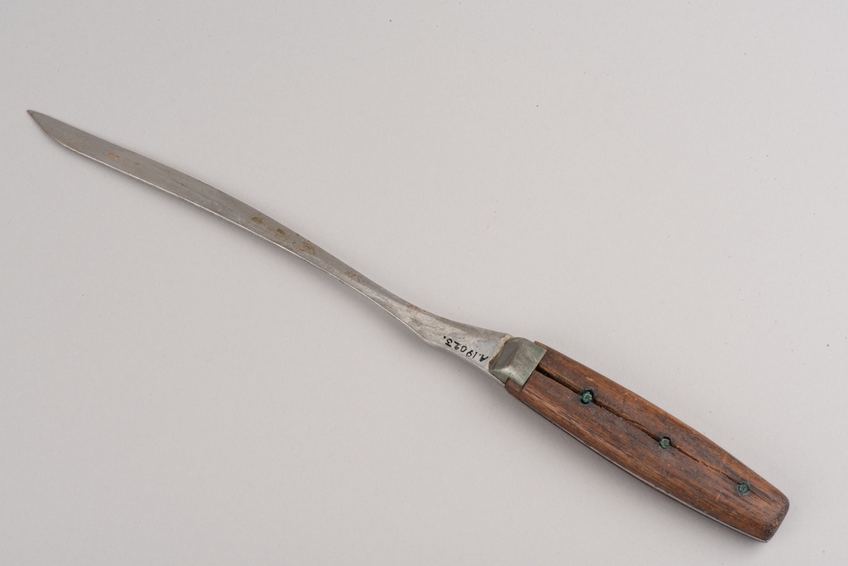 Kniv av stål med handtag av trä.
Bladet är starkt nedslipat och sitter fäst i handtaget med nitar. Tången går genom hela skaftet och är synligt på sidorna.
Kniven ska ha använts till slakt.