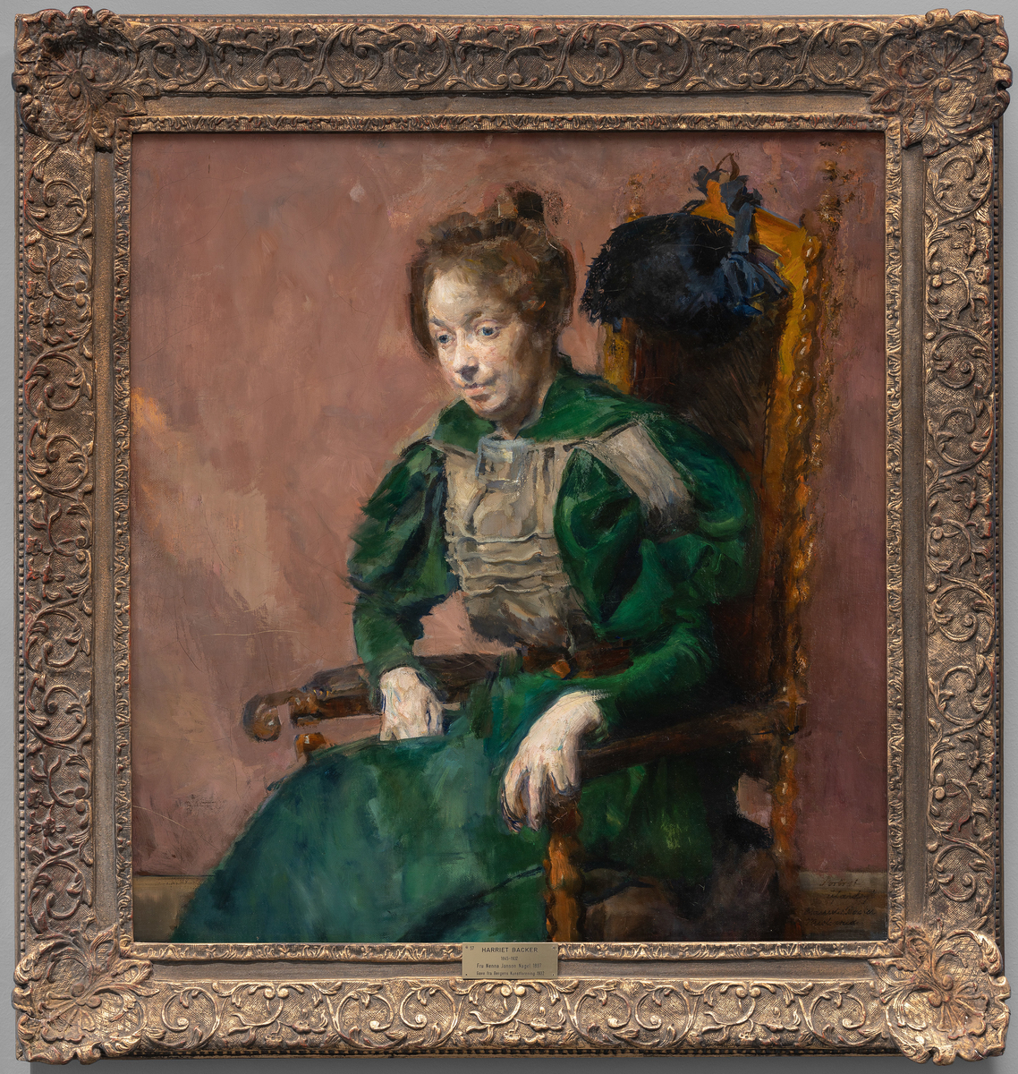 Ung kvinne i grønn kjole i en høyrygget gyllenlærstol vendt mot venstre. Venstre hånd hviler på armlenet. Oppsatt hår med topp.
