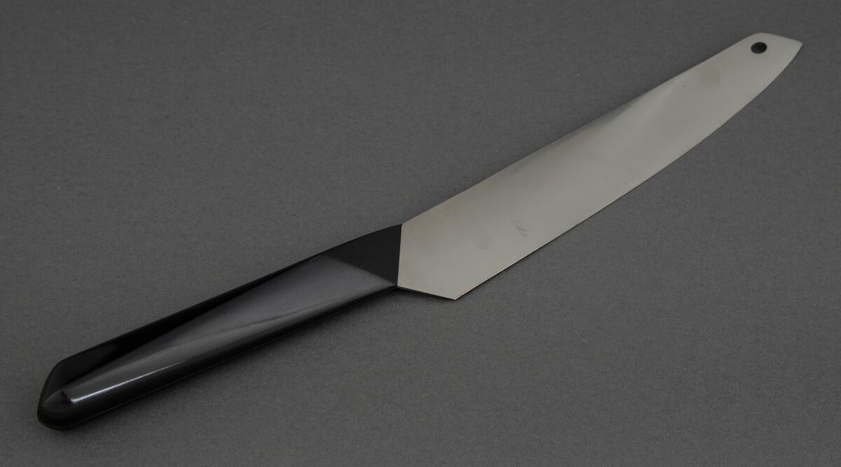 Skinkekniv i rustfritt stål med svart, kantete nylonskaft. Skaftet er festet skrått til bladet. Utstanset oval øverst i knivbladet for oppheng.
