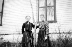 To kvinner ved et tre foran et hus ved Breidablikk.