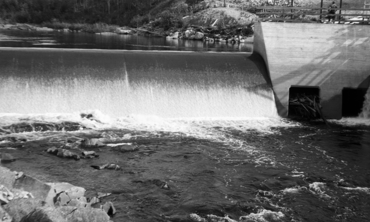 Kraftverksdammen ved Kvernfallet i elva Søre Osa i Åmot kommune i Hedmark, fotografert i motstrøms retning i 1938, to år etter at dette damanlegget sto ferdig. Det dreier seg om en forholdsvis lav terskel, en armert betongkonstruksjon med avrundet krone, plassert på tvers av elveløpet. Vanninntaket for turbinrøret befant seg ved søndre elvebredd (til høyre på dette fotografiet) der elveløpet var djupest. Sjølve kraftstasjonen ble lagt ved Brufallet, noen hundre meter nedenfor Kvernfalldammen.
