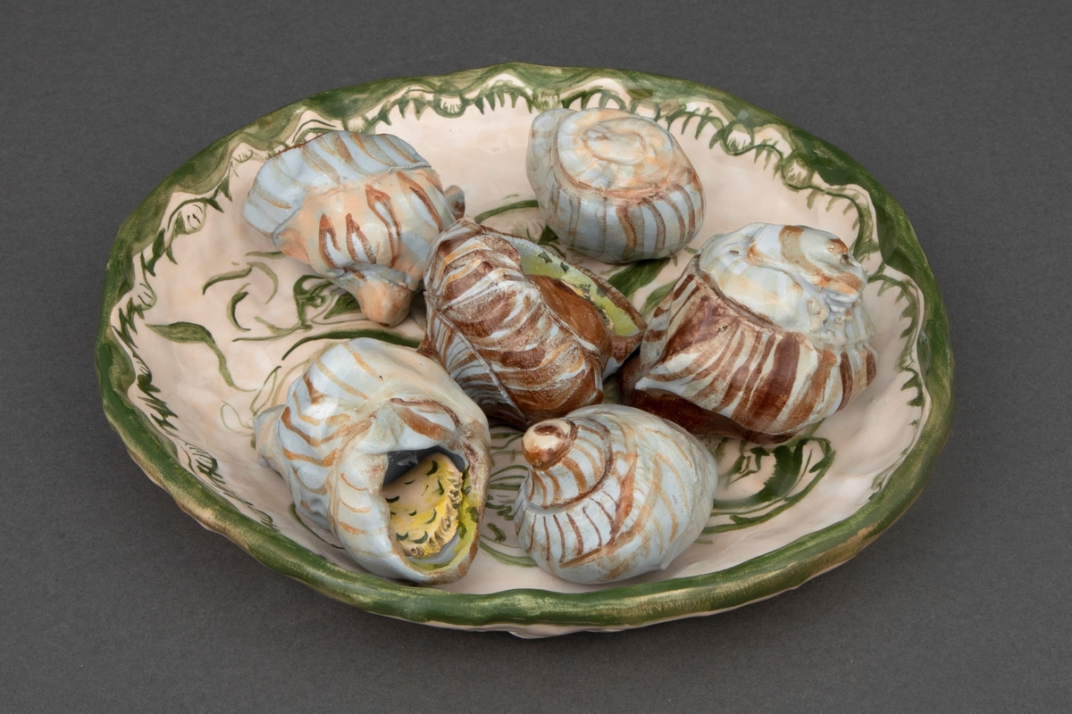 Fat med referanse til trompe l'oeil-stilleben i keramikk. På fatet ser vi escargot eller seks sneglehus med snegler i hvitløkssmør.