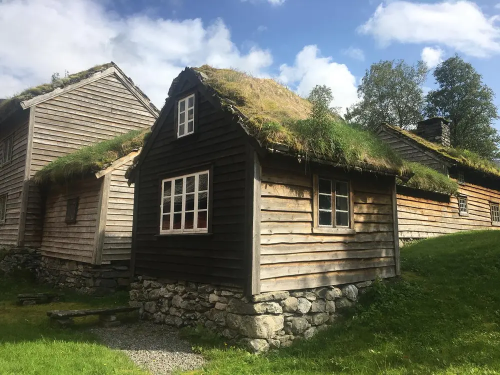 Gamle tjærebredde hus med steinmur og torvtak