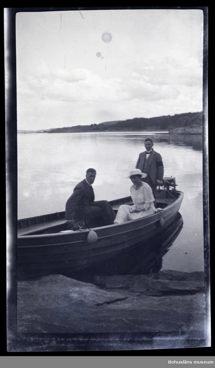 Tre personer i en båt vid en klipphäll.
