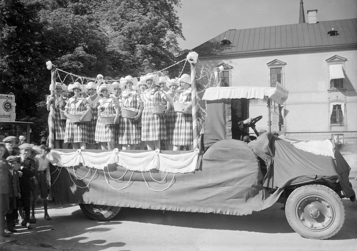 Glada miner i Linköping 1931, sannolikt i samband med firandet av Barnens Dag. Bilden visar kortegens färd över Borggården med bland andra AB Cloettas ekipage.