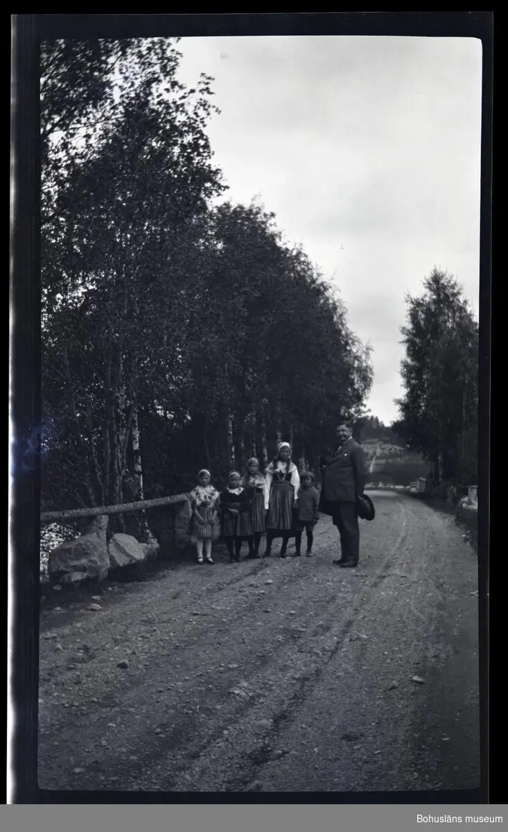 En man och fem barn ståendes på en grusväg.