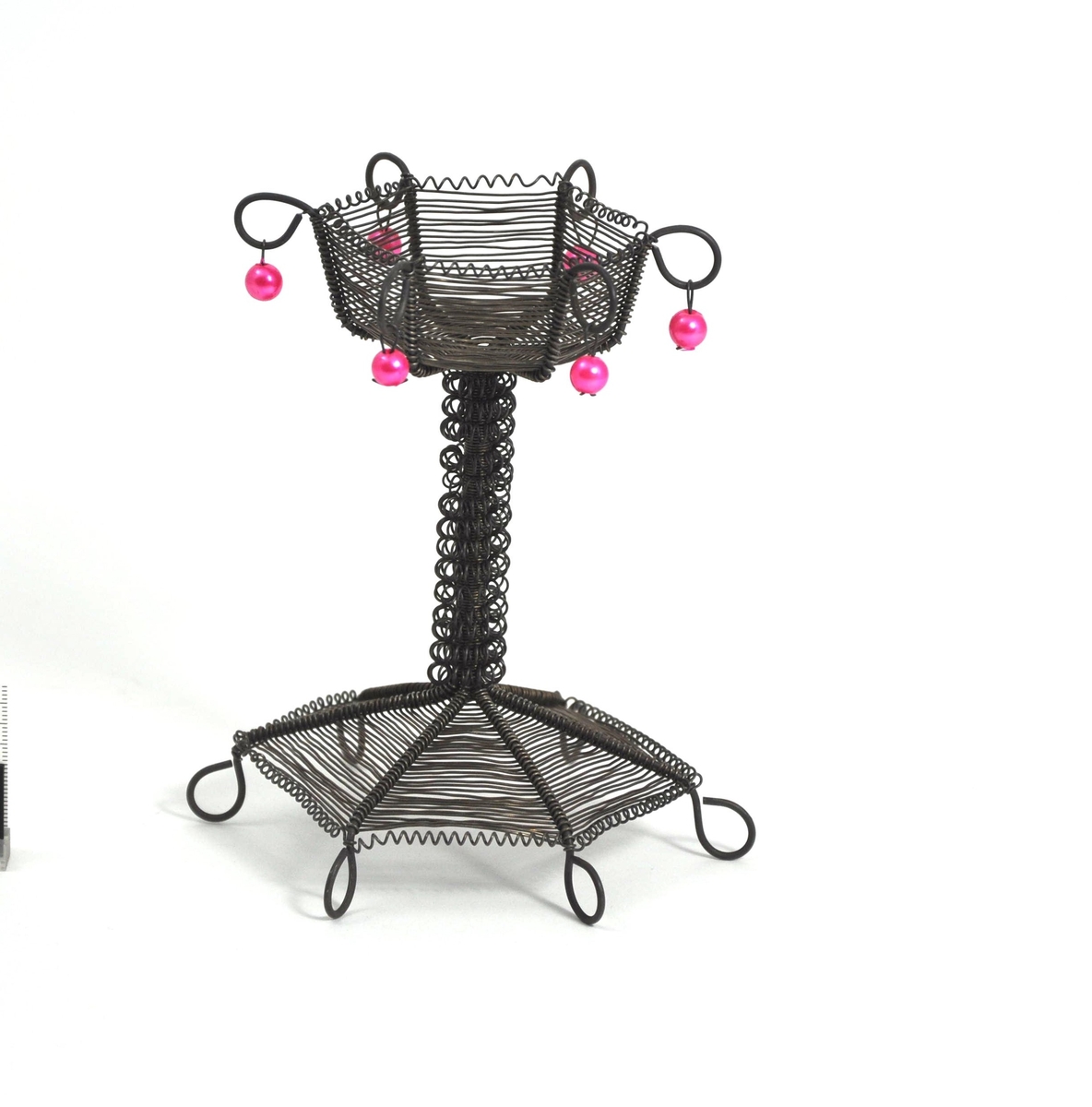 Lysestake for telys laget av ståltråd. Sekskantet fot og beholder til lys. Stett dekorert med spiral. Rosa perler i toppen.