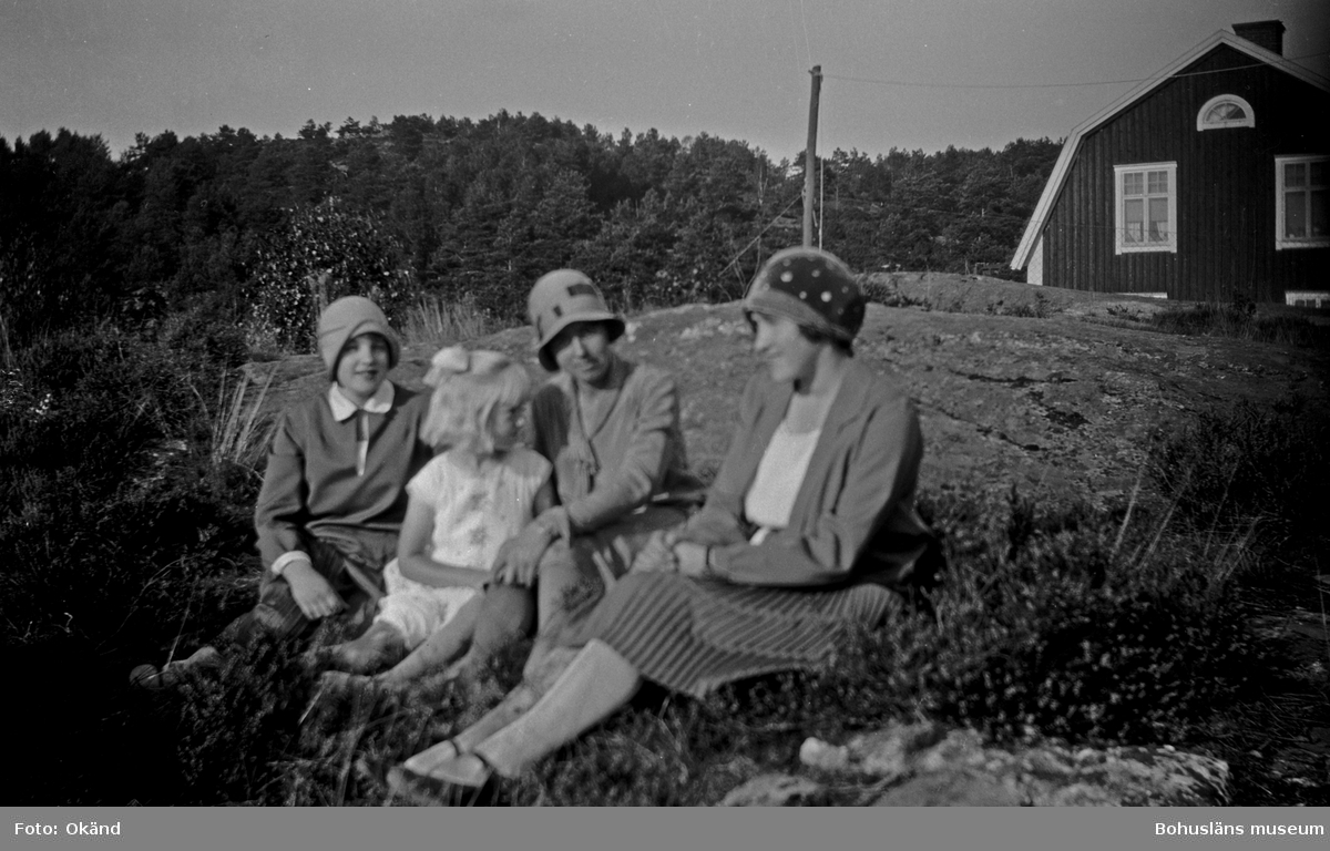 Fyra personer sittandes på en berghäll i en trädgård.