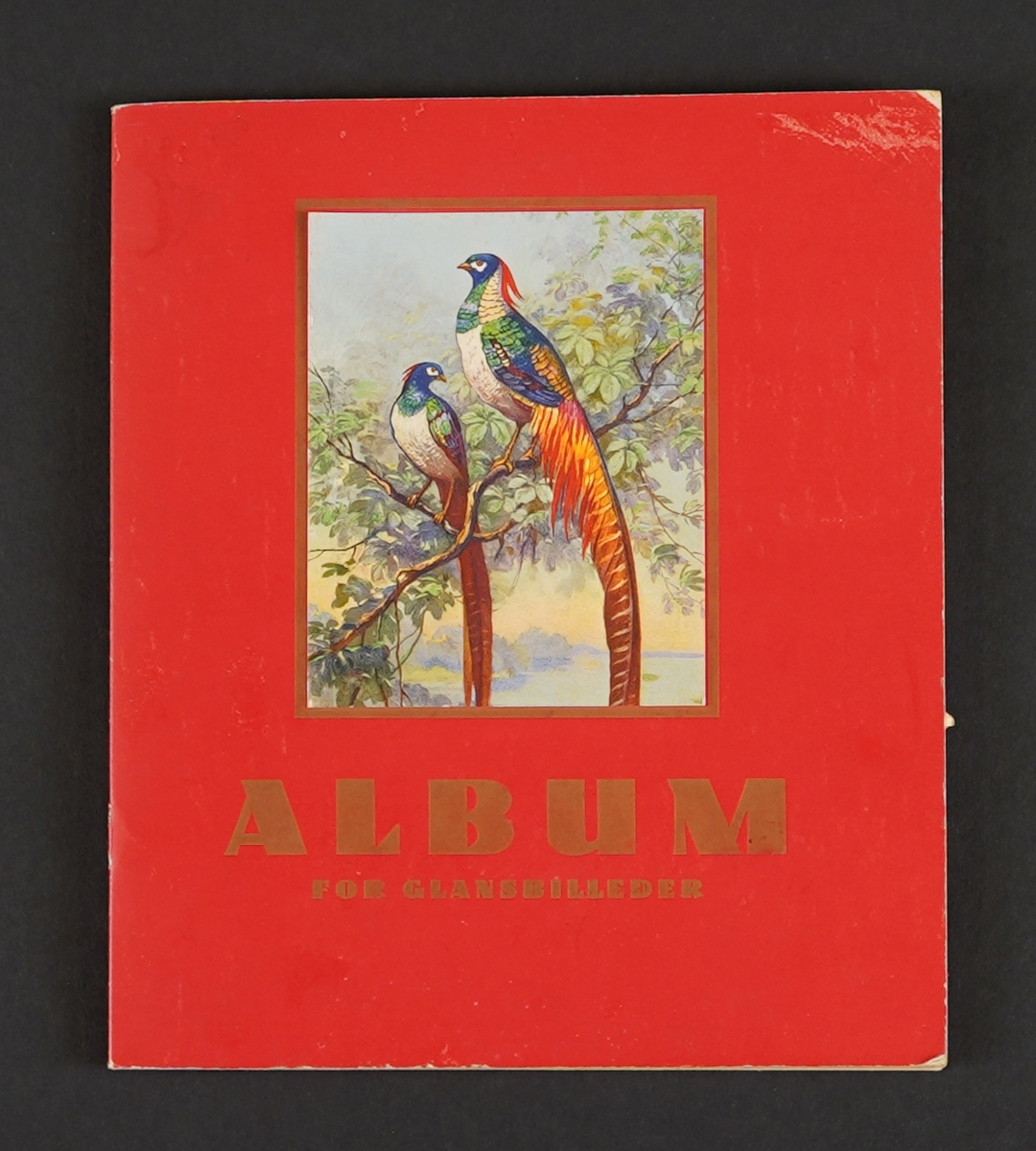 På framsida to påfuglar på ei grein. Glansbileta i boka er ulike motiv som: engel, bil, båt, fugl,dyr,eventyr, blomer, idrett, Donald