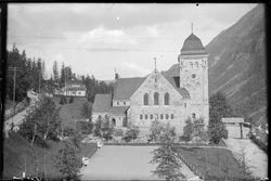 Rjukan kirke med park og grusplass foran kirken. Portal i tr