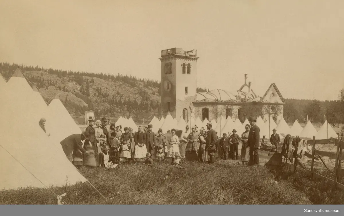 Sundsvalls stadsbrand 1888. Tältläger för bostadslösa med den nedbrunna kyrkan Lovisa Ulrika i bakgrunden.
