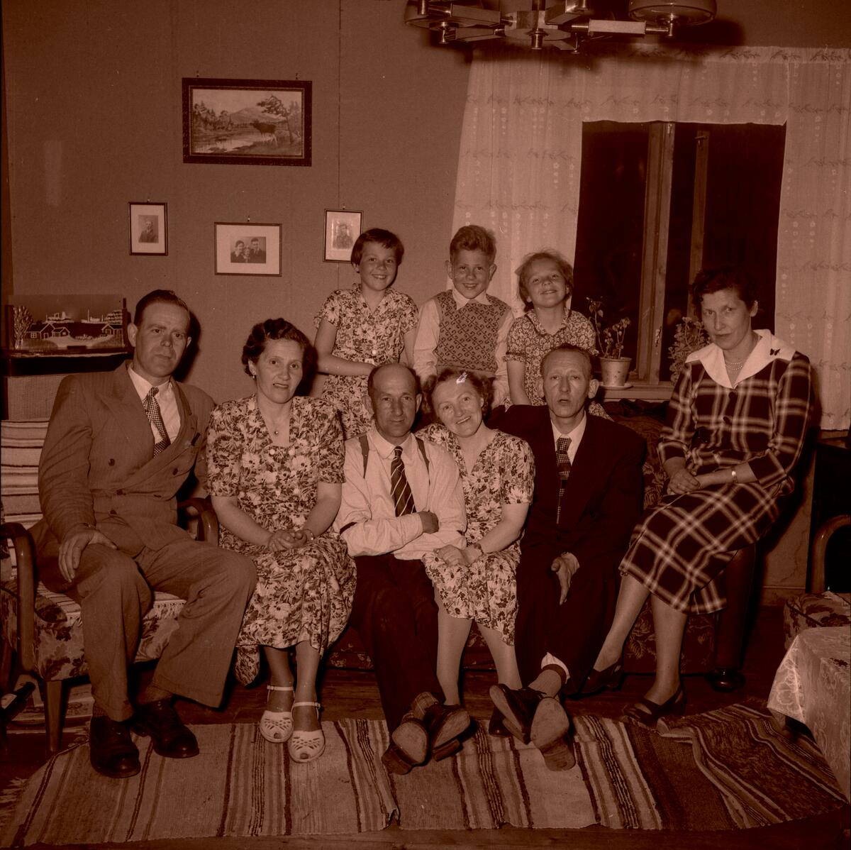 Gruppebilde av ni mennesker i en stue.