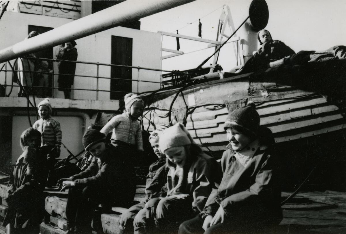 Mange barn ombord i båt på Adventfjorden på 50-tallet. Trygve Hansen på toppen av livbåten.