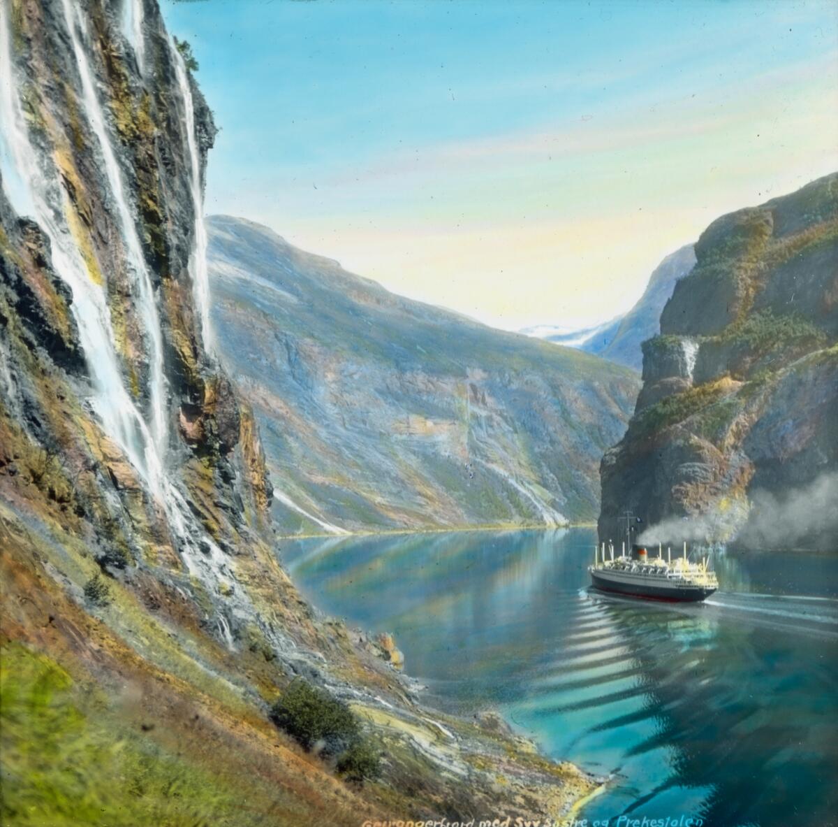 Håndkolorert dias. En passasjerskip er på vei innover Geirangerfjorden. Del av Wilses serie kalt "Når fjordene blåner". 