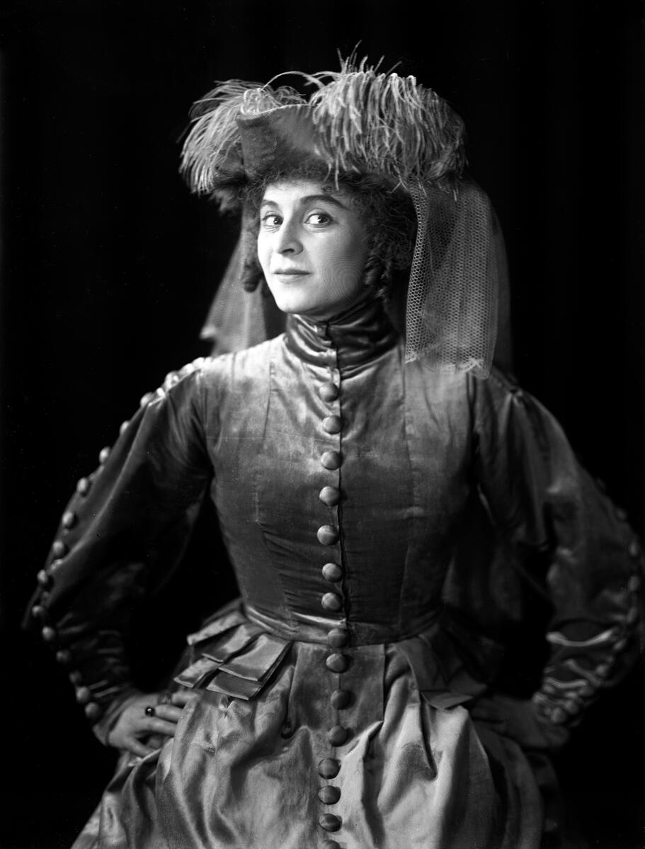 Portrett av skuespilleren og sceneinstruktøren Gerda Ring. Hun poserer i en kjole og en stor hatt med fjær.