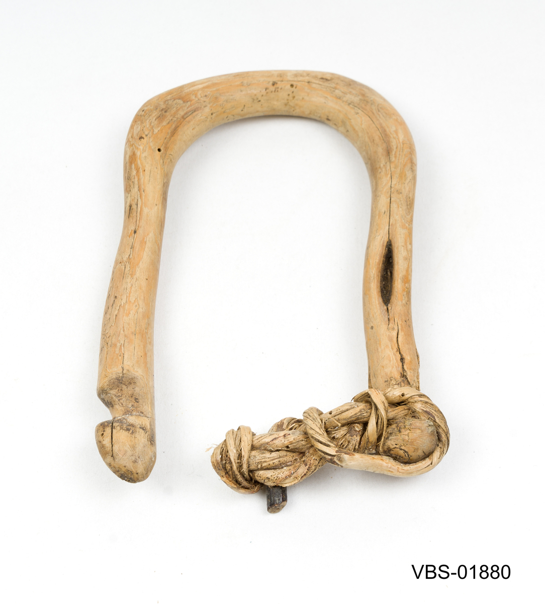 Laget av en hel einergrein, brettet i hesteskoform.
Rester av tau i knutet vegetabilsk fiber på den ene siden.