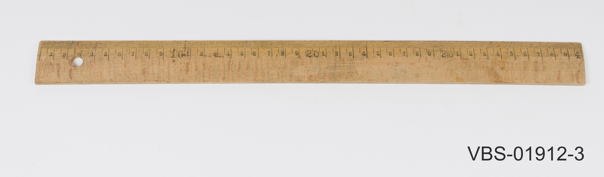 Trelinjal med hull til opphenging i venstre ende.
Tynnere på kanten der linjene er med måltallene i centimeter. 
Gjenstanden måler  centimeter (fra 1 til 40 cm).