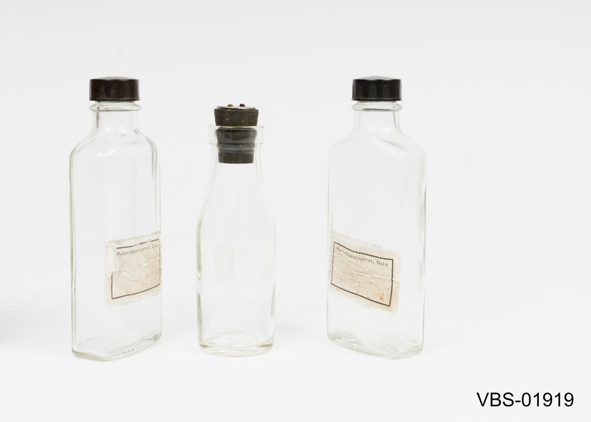 Laboratorieutstyr som består av 3 glassflasker laboratorie gjenstander av glass og en gummiproppen.
Gummiproppen har en rund aluminiumsplate spikret med to sifre: 77 

1 rund flaske med gummiplugg
2 flate flasker med skrukork