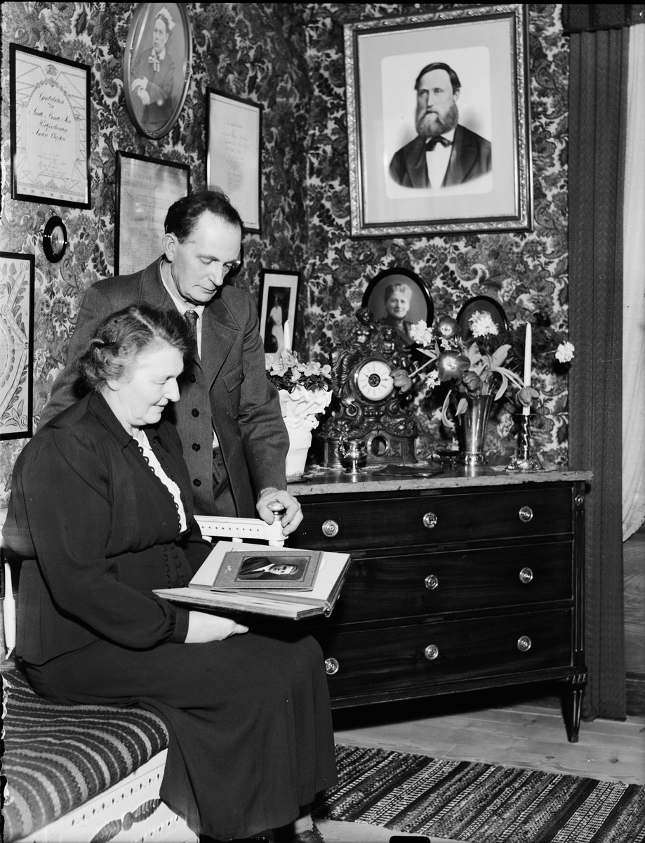 Anders Johnsson och en kvinna tittar i ett fotoalbum, Assjö, Uppland