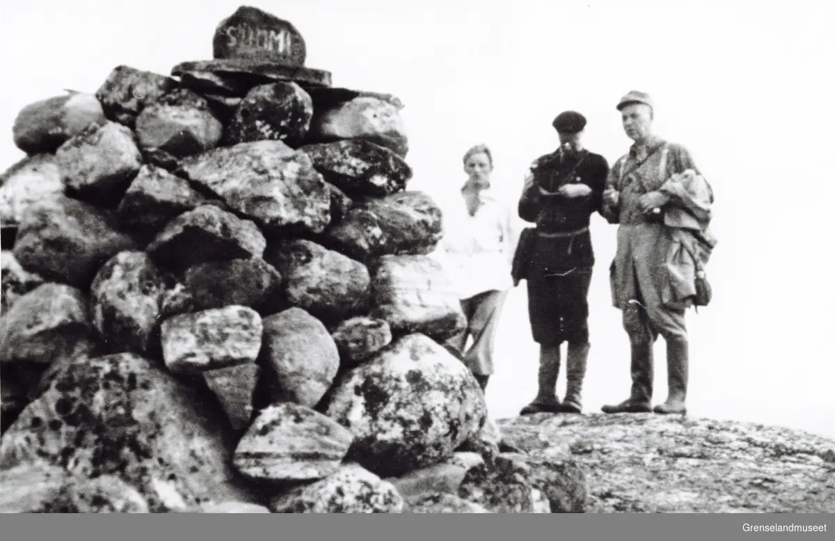 Grensebefaring i 1950. Tre personer står ved siden av en grenserøys merket med SUOMI. 