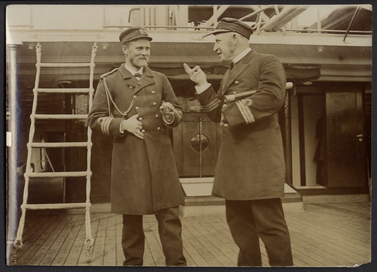Bilden visar två kaptener i samtal på ett örlogsfartyg. Båda har en kikare under armen. I bakgrunden syns kommandobryggan.