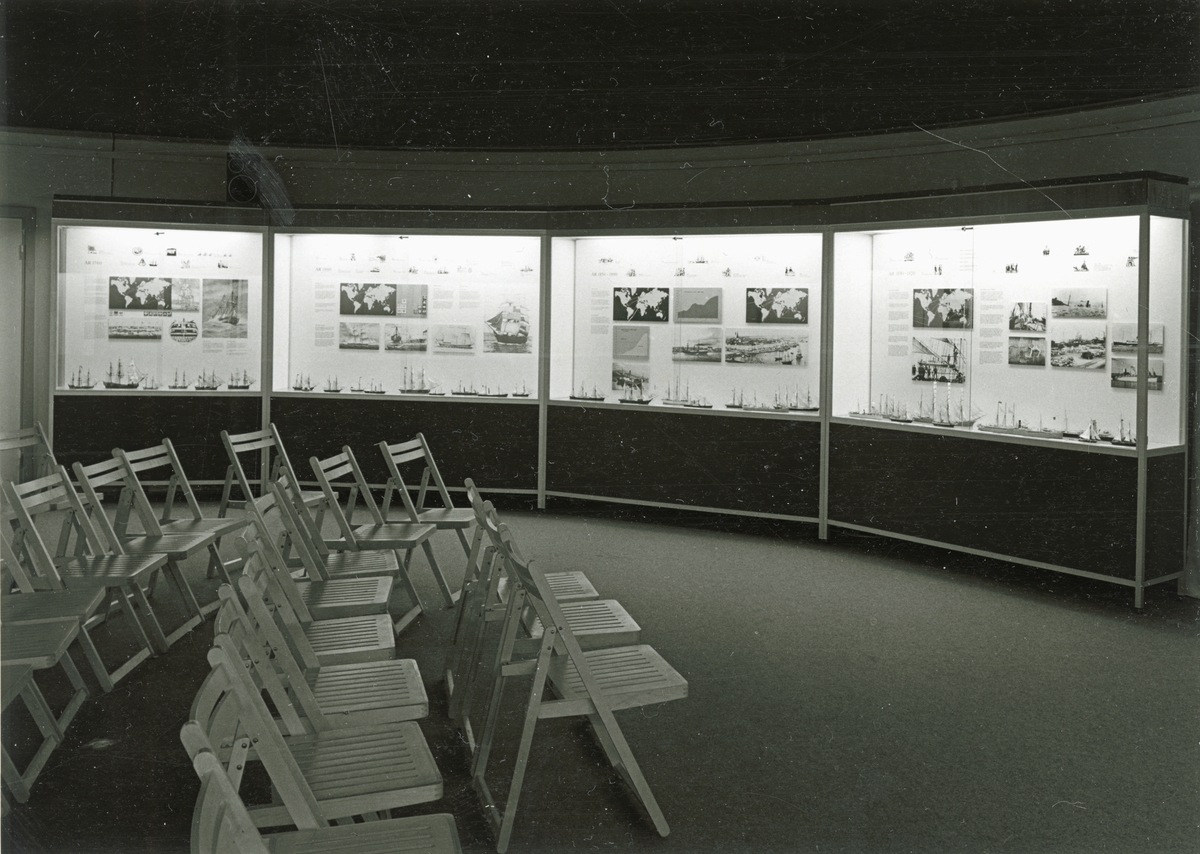 Sjöhistoriska museets permanenta utställning fotograferad 1987. Fyra montrar som visar sjöfart från 1700-tal fram till 1920-tal. Utställningsrummet är uppmöblerat med fällstolar för föreläsning.