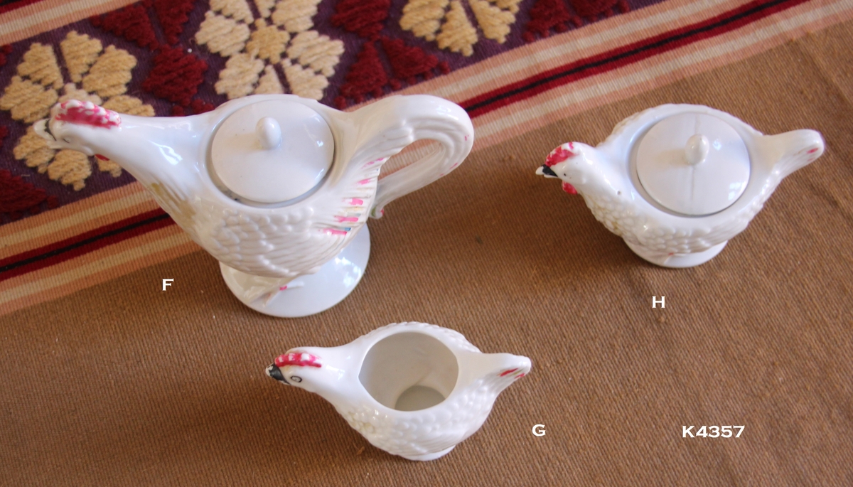 Koppestell i porselen:
4 kopper med underskål (a, b, c, d), 1 lite fat (e).
Koppene har mønster oppe. Hanken i gull. Rød kant nederst.
3 høner i hvit porselen med rød kam og fjærmønster på sidene (f, g, h).
1 Kaffekanne med lokk (f), 1 sukkerskål (g) og 1 fløtemugge (h).