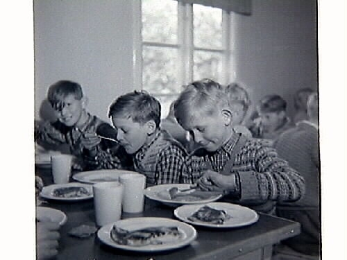 Barnbespisningen till skolan i Spannarp 1949 med byggnaden samt ätande elever och personal.