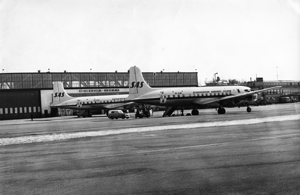 To av SAS sine DC-6B, med registreringsnummer OY-KMI og SE-BDU, oppstilt på Bromma Flyplass i Stockholm.